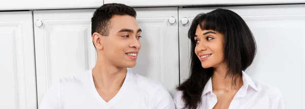 Interracial Couple Smiling Looking Each Other Kitchen Cabinets Panoramic Shot — Stock Photo, Image