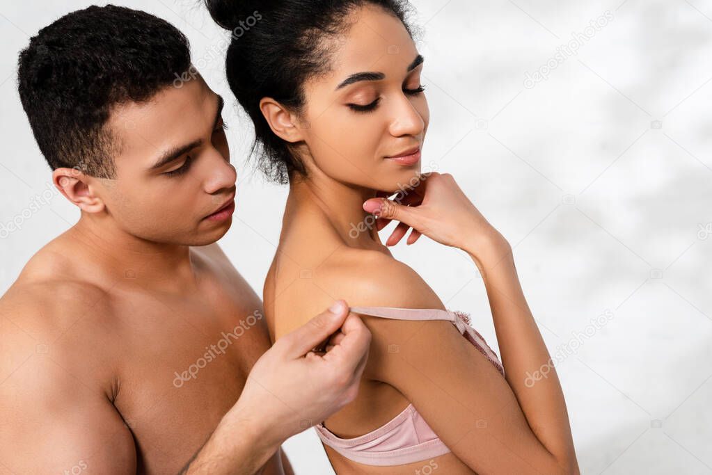 Man behind african american woman pulling bra strap on white