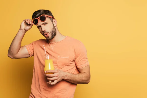 Jovem Animado Tocando Óculos Sol Enquanto Segurava Vidro Suco Laranja — Fotografia de Stock