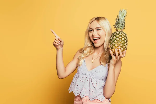 Fröhliches Blondes Mädchen Hält Ananas Der Hand Und Zeigt Mit — Stockfoto