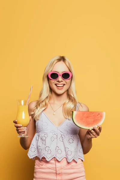 Uśmiechnięta Blondynka Okularach Przeciwsłonecznych Trzymająca Szklankę Soku Pomarańczowego Plasterek Arbuza — Zdjęcie stockowe
