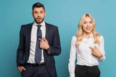surprised businessman and businesswoman pointing with fingers at themselves on blue background clipart