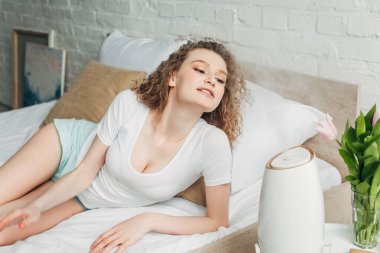 beautiful happy girl on bed with air purifier clipart
