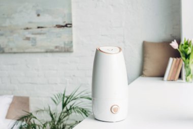 white humidifier standing on windowsill at home clipart