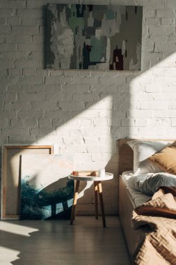 Yatak odasının içinde yastıklar ve gölgeli güneş ışığında resimler var.
