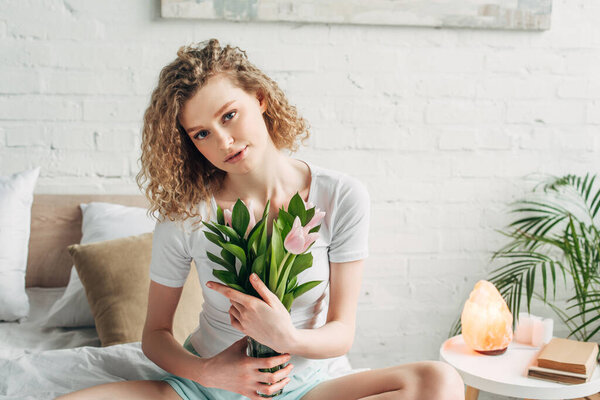 curly girl holding tulips in bedroom with Himalayan salt lamp