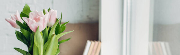 selective focus of pink tulip flowers on windowsill with books, panoramic crop