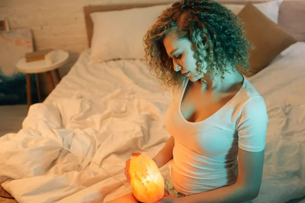 Beautiful Curly Girl Holding Himalayan Salt Lamp While Sitting Bed — Stock Photo, Image