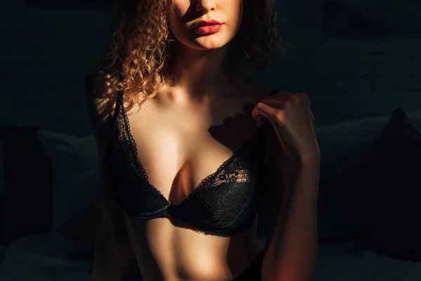 阳光下穿着黑色胸罩的性感卷曲女孩在床上的剪影 — 图库照片