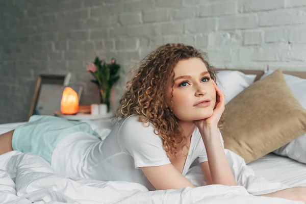美しい夢のような家の中の女の子はヒマラヤ塩ランプ付きのベッドルームでベッドの上に横たわる — ストック写真