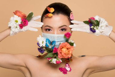 Lateks eldivenli ve çiçekli maskeli bej rengi kelebekli çekici Asyalı kadın.