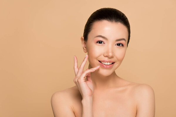 happy tender naked asian woman with perfect clean skin isolated on beige