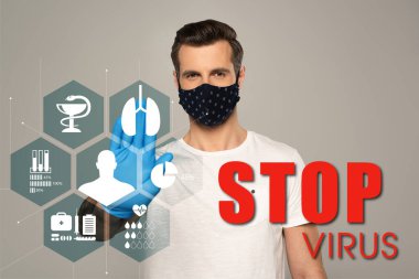 Güvenlik maskeli ve lateks eldivenli bir adam gri üzerinde durdurma hareketi gösteriyor. Virüs harflerini ve tıbbi işaretleri göstermeyi bırakın. 