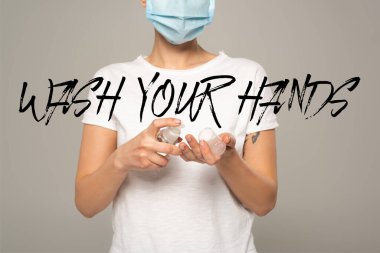 Griye izole edilmiş el dezenfektanı kullanan tıbbi maskeli kadın, ellerini yıka.