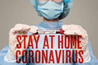 Selective focus of doctor holding test tube with blood sample of coronavirus lettering isolated on grey, stay at home coronavirus illustration clipart