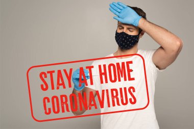 Güvenlik maskeli bir adam ve termometre tutan lateks eldivenli ve alnına dokunan gri renkli adam, evde kalıp Coronavirus çizimini yapın. 