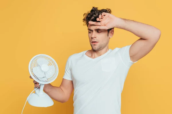 Verward Man Met Opgeheven Hand Kijkend Naar Bureau Ventilator Geïsoleerd — Stockfoto