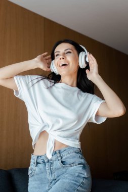 Neşeli kız evde kulaklıkla dans edip müzik dinliyor.