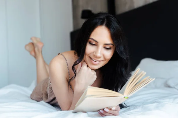 Evdeki Yatakta Kitap Okuyan Gülümseyen Genç Kadın — Stok fotoğraf