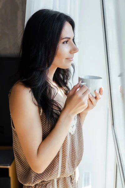 Vacker Flicka Som Håller Kopp Kaffe Och Tittar Genom Fönstret — Stockfoto