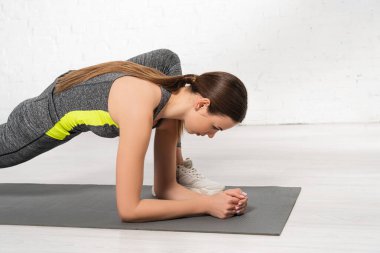Sportif genç kadın profili spor minderinde ısınıyor 