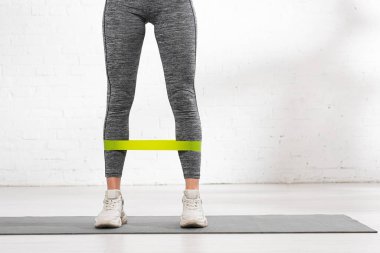 Sportif kız ve direniş bandı fitness minderinin üzerinde duruyor.