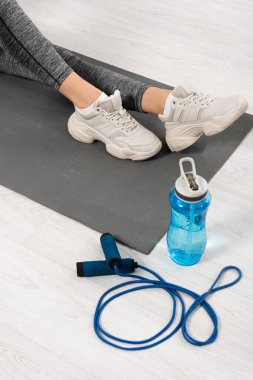 Sportif kızın spor minderinin yanında su ve ip atlarken çekilmiş görüntüsü. 