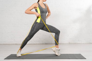 Sportif bir kadının, elleri kalçasında spor bandıyla spor yaparken çekilmiş görüntüsü. 