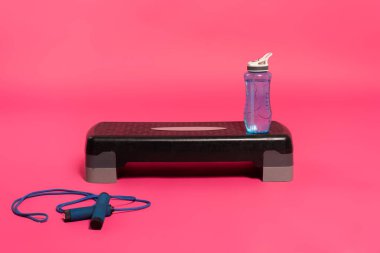 Spor şişesi, adım platformunda taze suyla Pembe üzerinde ip atlamak 