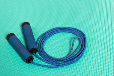 Turkuaz fitness paspasında mavi atlama ipi