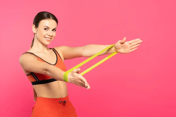 快乐的女运动员与用粉红隔离的电阻带一起锻炼 — 图库照片