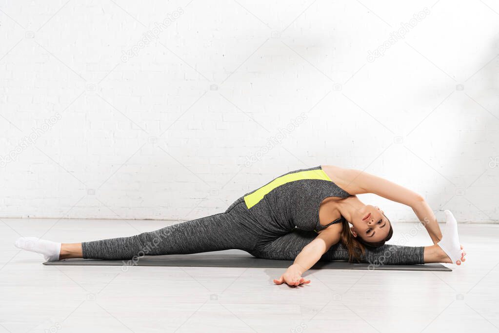 young flexible woman stretching on fitness mat 