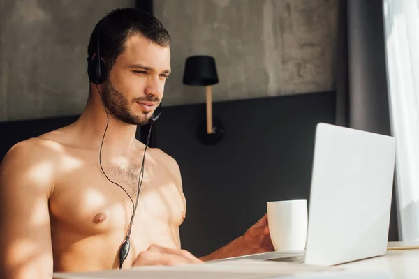 Bärtiger Und Hemdloser Bediener Headset Haltebecher Der Nähe Des Laptops — Stockfoto