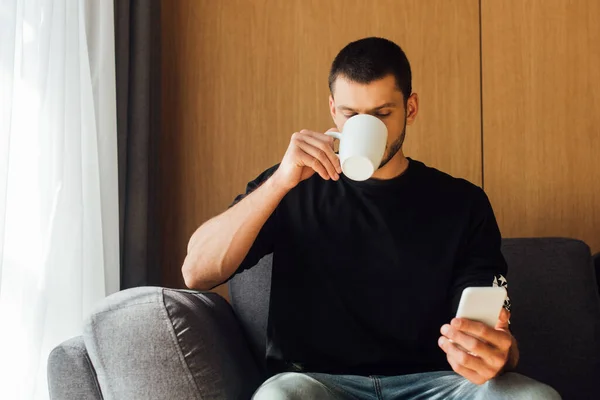 Mann Trinkt Kaffee Und Benutzt Smartphone Wohnzimmer — Stockfoto