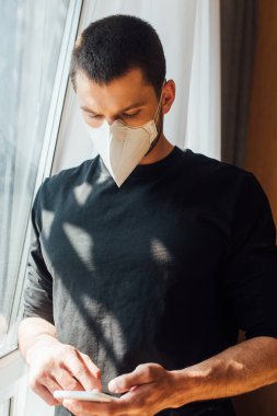 Akıllı telefon kullanan tıbbi maskeli bir adamın seçici odak noktası 