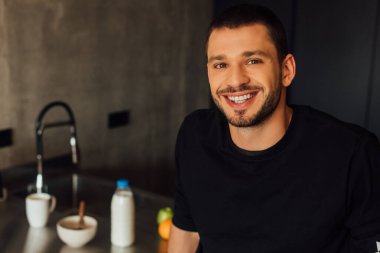 Mutlu sakallı adam gülümsüyor ve kameraya bakıyor.