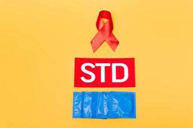 red ribbon as hiv awareness near std lettering and condoms isolated on orange  clipart