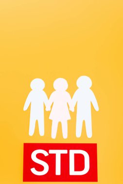 top view of three paper people near red paper with std lettering isolated on orange clipart