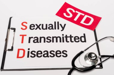 top view of clipboard with sexually transmitted diseases near red paper with std lettering and stethoscope isolated on white clipart