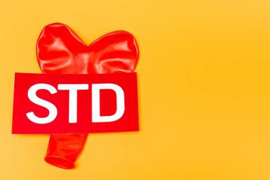 STD harflerinin yanındaki kalp şeklindeki balonun üst görüntüsü turuncu üzerine izole edilmiş. 