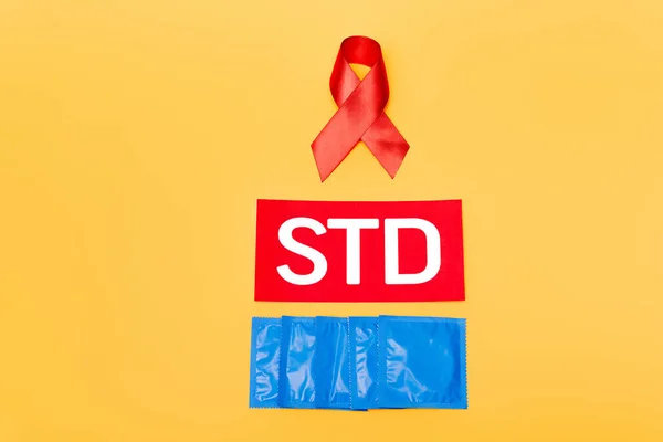 Rött Band Som Hiv Medvetenhet Nära Std Bokstäver Och Kondomer — Stockfoto