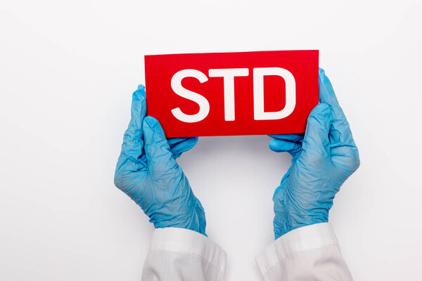 top view of doctor in blue latex gloves holding paper with std lettering isolated on white 