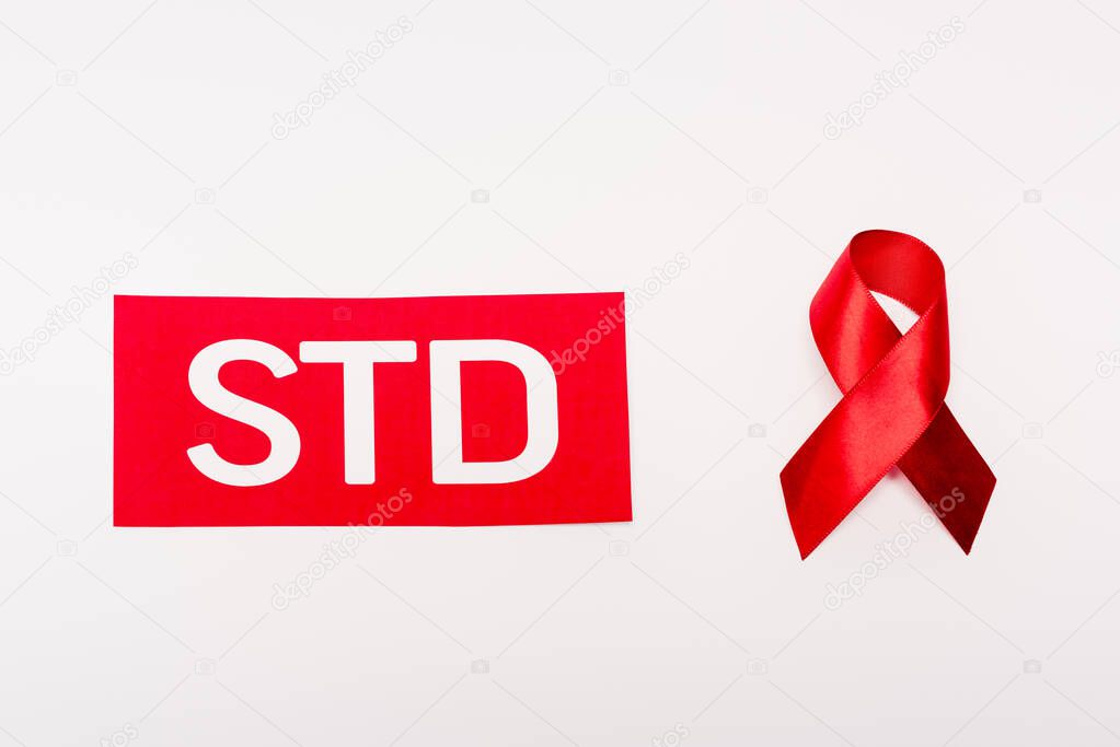 top view of red ribbon near paper with std lettering isolated on white 