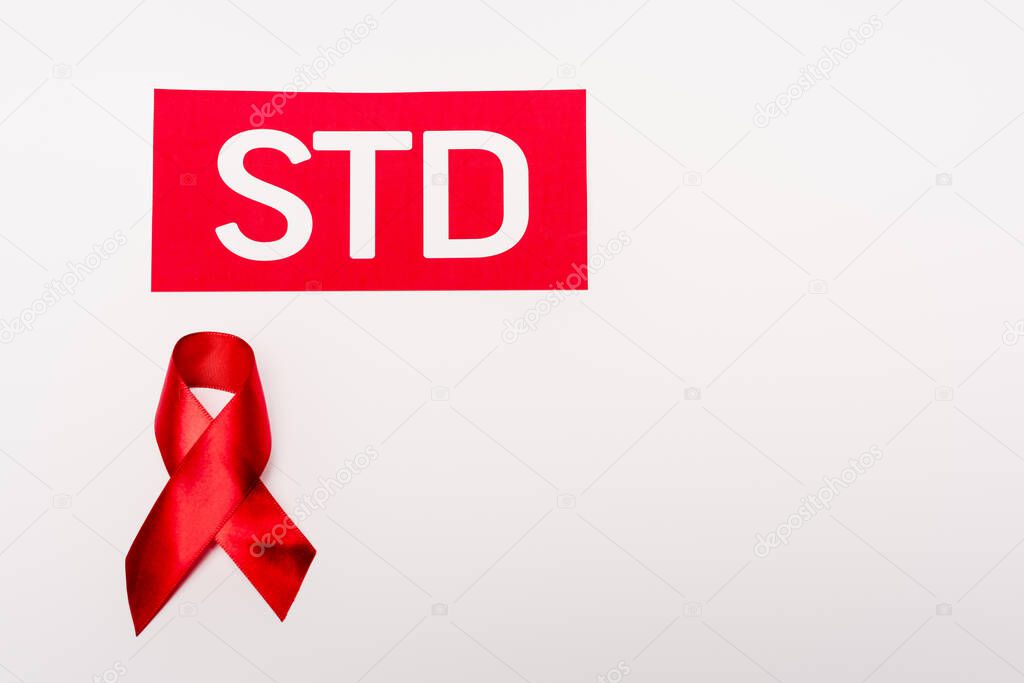 top view of red ribbon near std lettering isolated on white 