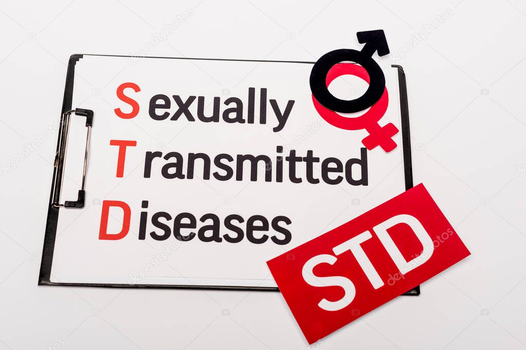 top view of clipboard with sexually transmitted diseases near gender symbols and std lettering isolated on white