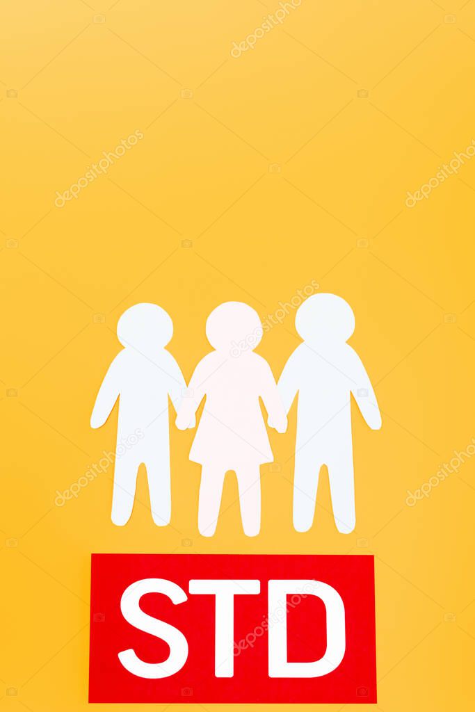 top view of three paper people near red paper with std lettering isolated on orange