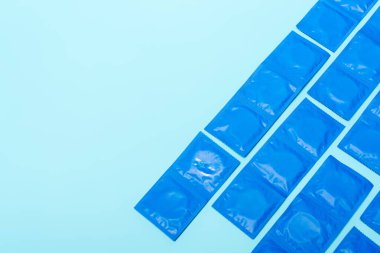 top view of packs with condoms isolated on blue with copy space clipart