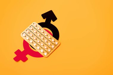 Doğum kontrol hapları ve turuncuya izole edilmiş cinsiyet sembolleriyle dolu su toplayıcı paketinin üst görüntüsü 