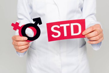 Beyaz önlüklü doktorun elinde cinsiyet sembolleri ve gri harflerle izole edilmiş... 