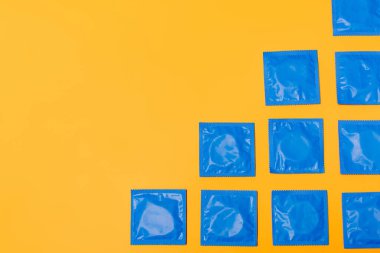 top view of condoms isolated on orange with copy space clipart